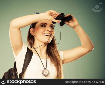 Summer holidays and tourism concept. Lovely tourist woman with backpack compass looking through binoculars filtered photo