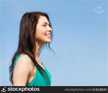 summer holidays and vacation - beautiful smiling girl over blue sky