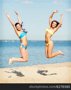summer holidays and vacation concept - beautiful girls in bikini jumping on the beach