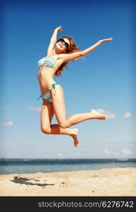 summer holidays and vacation concept - beautiful woman in bikini jumping on the beach