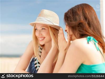 summer holidays and vacation concept - girls gossiping in cafe on the beach