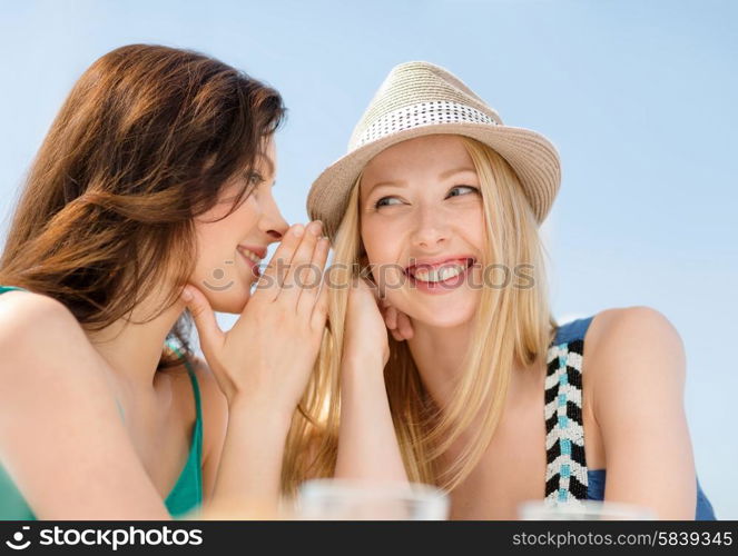 summer holidays and vacation concept - girls gossiping in cafe on the beach. girls gossiping in cafe on the beach