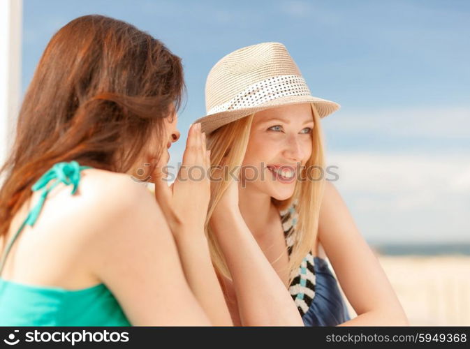 summer holidays and vacation concept - girls gossiping in cafe on the beach. girls gossiping in cafe on the beach