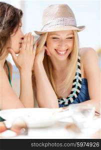 summer holidays and vacation concept - girls gossiping in cafe on the beach. girls gossiping in cafe on the beach