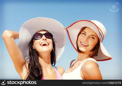 summer holidays and vacation concept - girls in hats on the beach