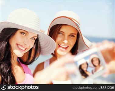 summer holidays and vacation concept - girls taking self portrait on the beach