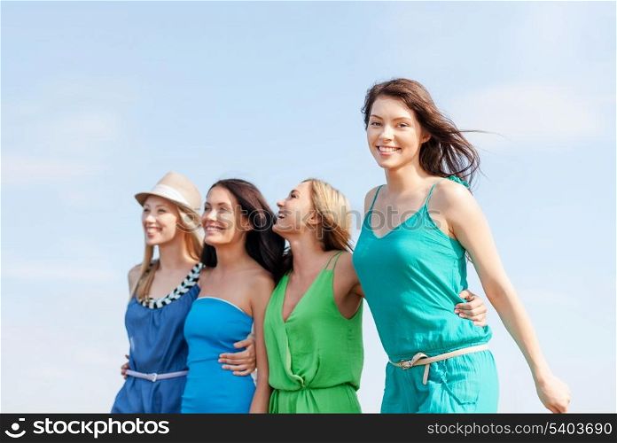 summer holidays and vacation concept - girls walking on the beach