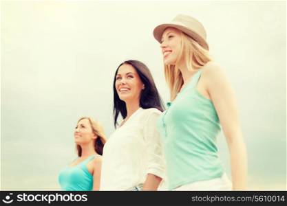 summer holidays and vacation concept - group of smiling girls chilling on the beach