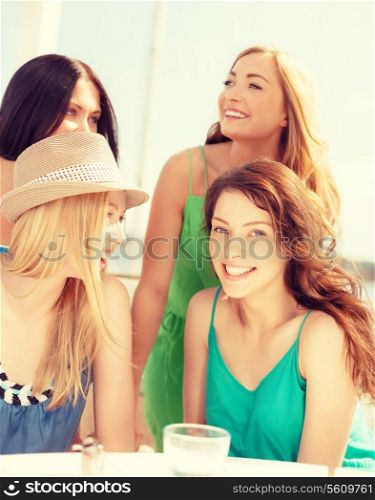 summer holidays and vacation concept - group of smiling girls in cafe on the beach