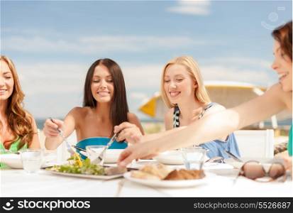 summer holidays and vacation concept - smiling girls in cafe on the beach