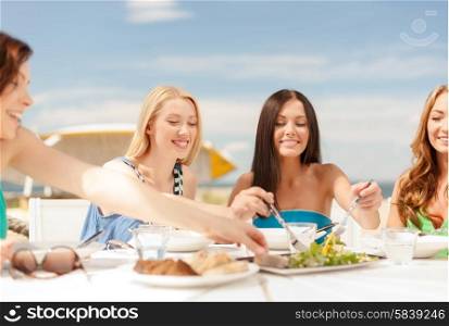 summer holidays and vacation concept - smiling girls in cafe on the beach. smiling girls in cafe on the beach