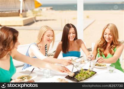 summer holidays and vacation concept - smiling girls in cafe on the beach. smiling girls in cafe on the beach