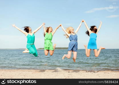 summer holidays and vacation concept - smiling girls jumping on the beach. smiling girls jumping on the beach