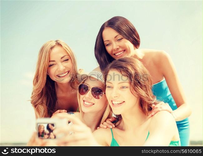 summer holidays and vacation concept - smiling girls taking photo in cafe on the beach