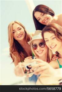 summer holidays and vacation concept - smiling girls taking photo in cafe on the beach
