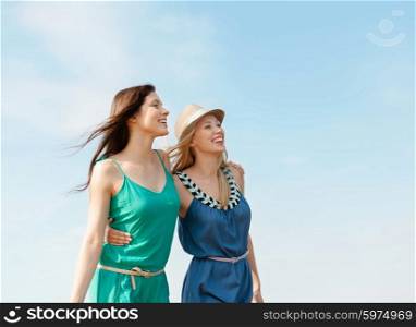 summer holidays and vacation concept - smiling girls walking on the beach. smiling girls walking on the beach