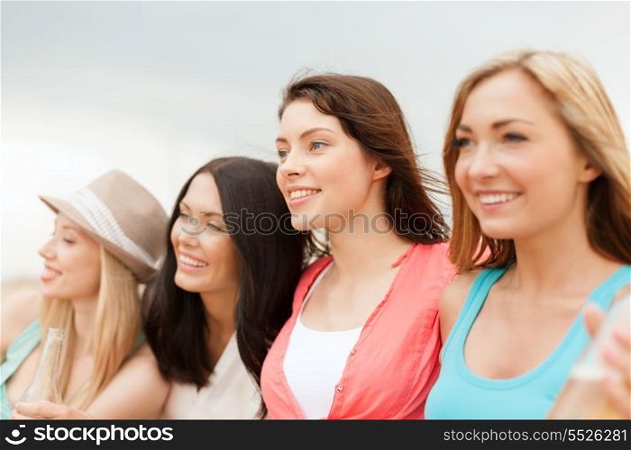 summer holidays and vacation concept - smiling girls with drinks on the beach