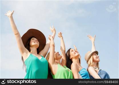summer holidays and vacation concept - smiling girls with hands up on the beach. smiling girls with hands up on the beach