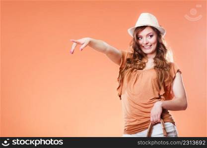 Summer holidays and vacation. Girl in fashionable clothes straw hat holding bag handbag. attractive woman tourist pointing copy space with finger on brown