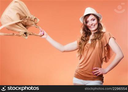 Summer holidays and vacation. Girl in fashionable clothes straw hat playing with bag handbag. Portrait of attractive woman tourist on brown