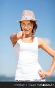 summer holidays and vacation - girl in hat pointing at you on the beach