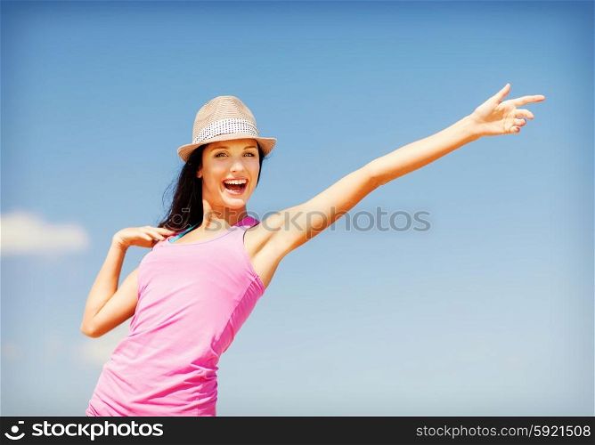 summer holidays and vacation - girl in hat showing direction on the beach. girl in hat showing direction on the beach