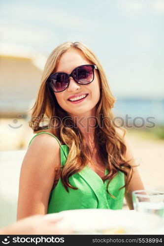 summer holidays and vacation - girl in shades in cafe on the beach