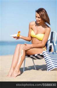summer holidays and vacation - girl putting sun protection cream on the beach chair