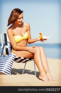 summer holidays and vacation - girl putting sun protection cream on the beach chair. girl sunbathing on the beach chair