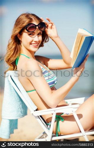 summer holidays and vacation - girl reading book on the beach chair