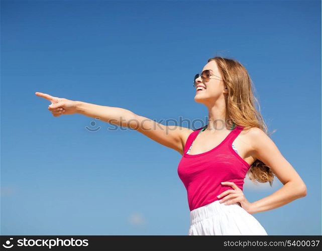 summer holidays and vacation - girl showing direction on the beach