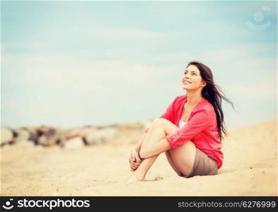 summer holidays and vacation - girl sitting on the beach