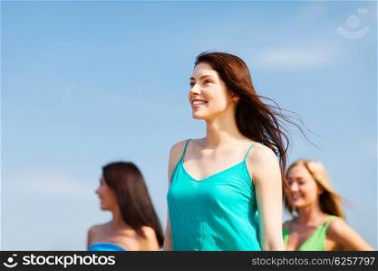 summer holidays and vacation - girl with friends walking on the beach. girl with friends walking on the beach