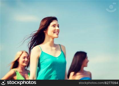 summer holidays and vacation - girl with friends walking on the beach