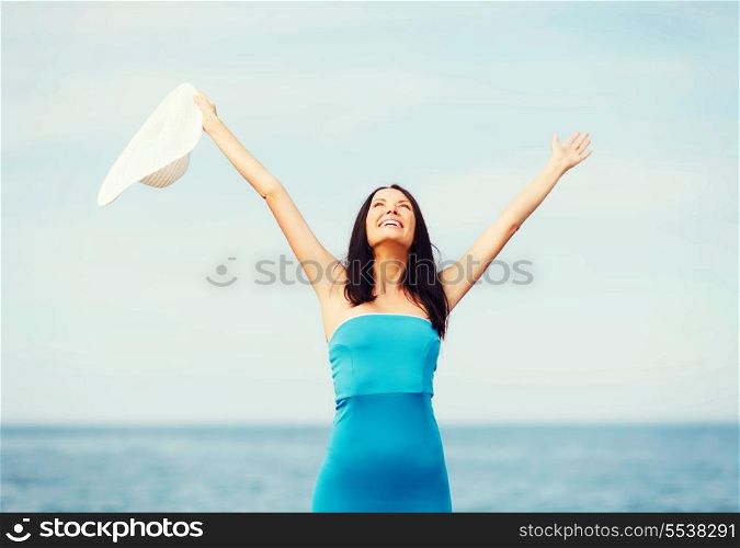 summer holidays and vacation - girl with hands up on the beach