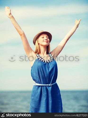 summer holidays and vacation - girl with hands up on the beach