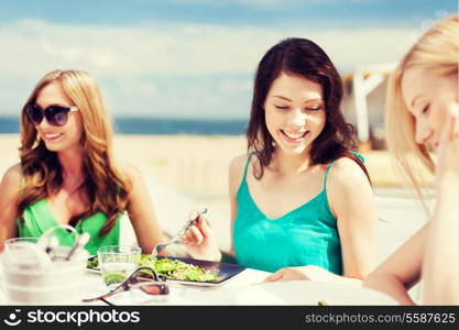 summer holidays and vacation - girls eating and drinking in cafe on the beach