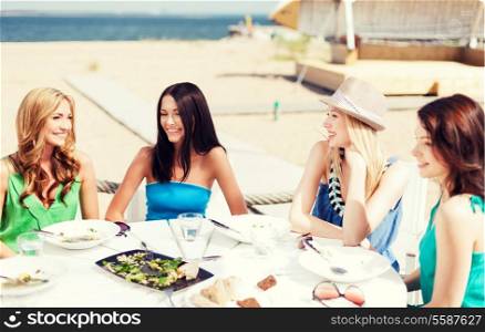 summer holidays and vacation - girls eating and drinking in cafe on the beach