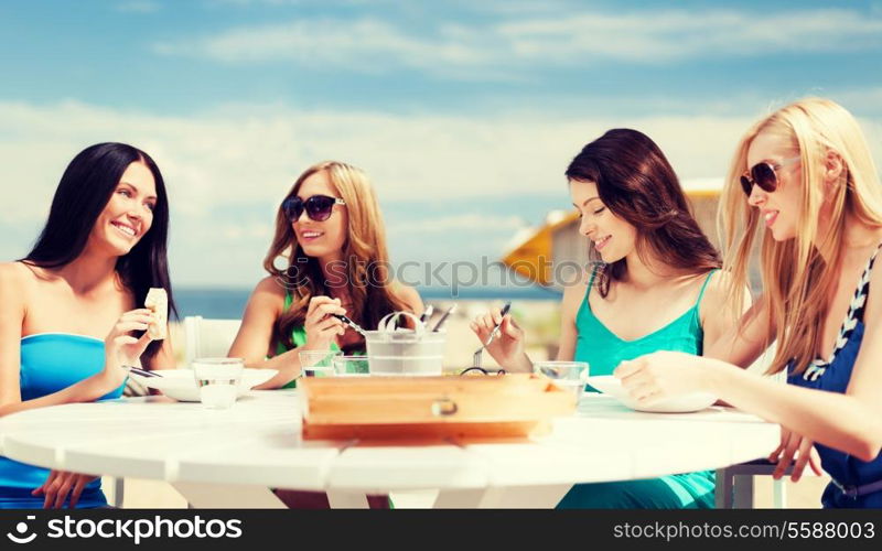 summer holidays and vacation - girls eating and drinking in cafe on the beach