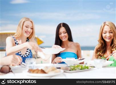 summer holidays and vacation - girls eating and drinking in cafe on the beach. girls in cafe on the beach