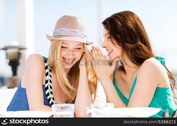 summer holidays and vacation - girls gossiping in cafe on the beach