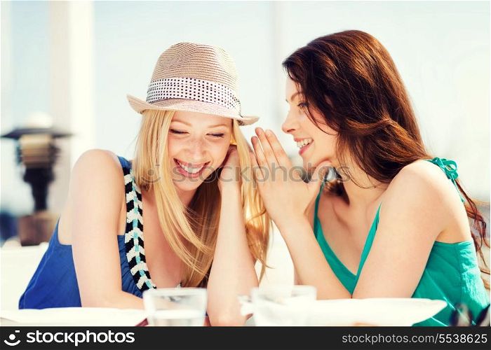 summer holidays and vacation - girls gossiping in cafe on the beach