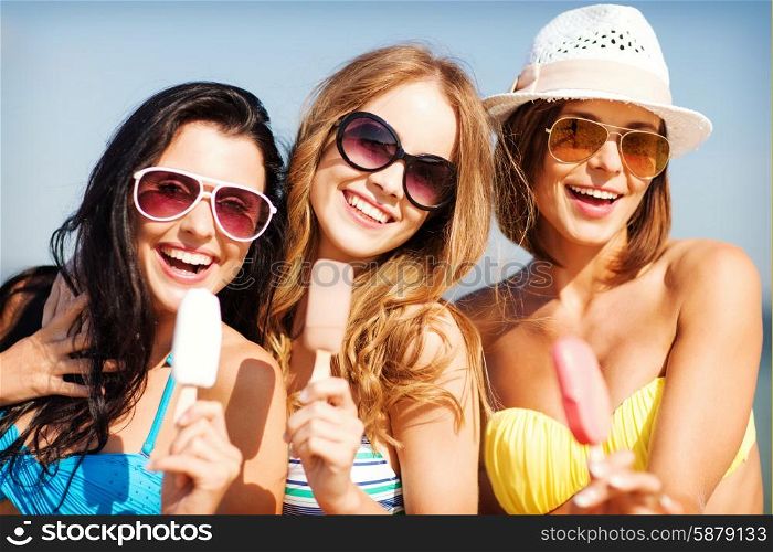 summer holidays and vacation - girls in bikinis eating ice cream on the beach. girls in bikinis with ice cream on the beach