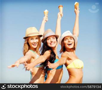 summer holidays and vacation - girls in bikinis eating ice cream on the beach. girls in bikinis with ice cream on the beach