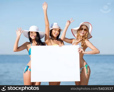 summer holidays and vacation - girls in bikinis holding blank white board on the beach