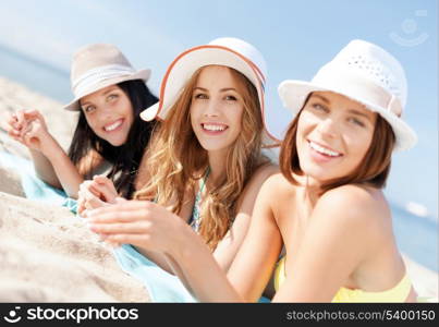 summer holidays and vacation - girls in bikinis sunbathing on the beach