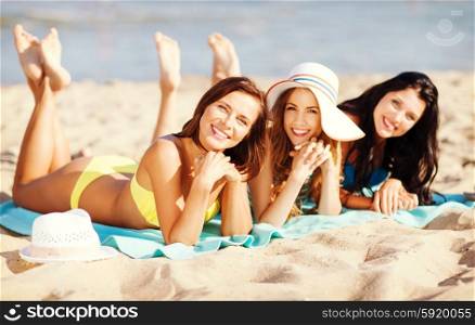 summer holidays and vacation - girls in bikinis sunbathing on the beach. girls sunbathing on the beach