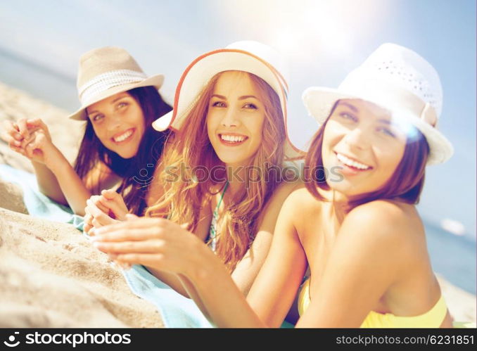 summer holidays and vacation - girls in bikinis sunbathing on the beach. girls sunbathing on the beach