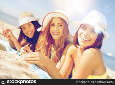 summer holidays and vacation - girls in bikinis sunbathing on the beach. girls sunbathing on the beach