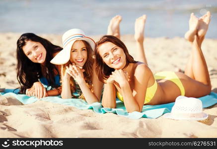 summer holidays and vacation - girls in bikinis sunbathing on the beach